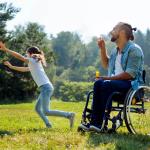 Un homme en fauteuil roulant et sa fille font des bulles de savon pour s'amuser.